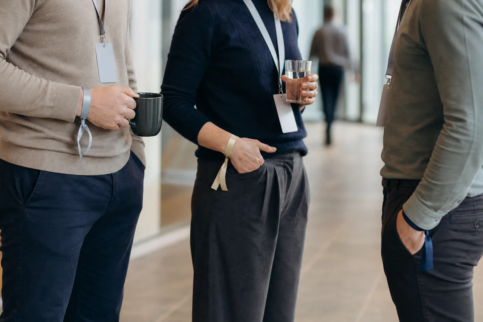 Tre personer med olika armband i en konferensfoajé.