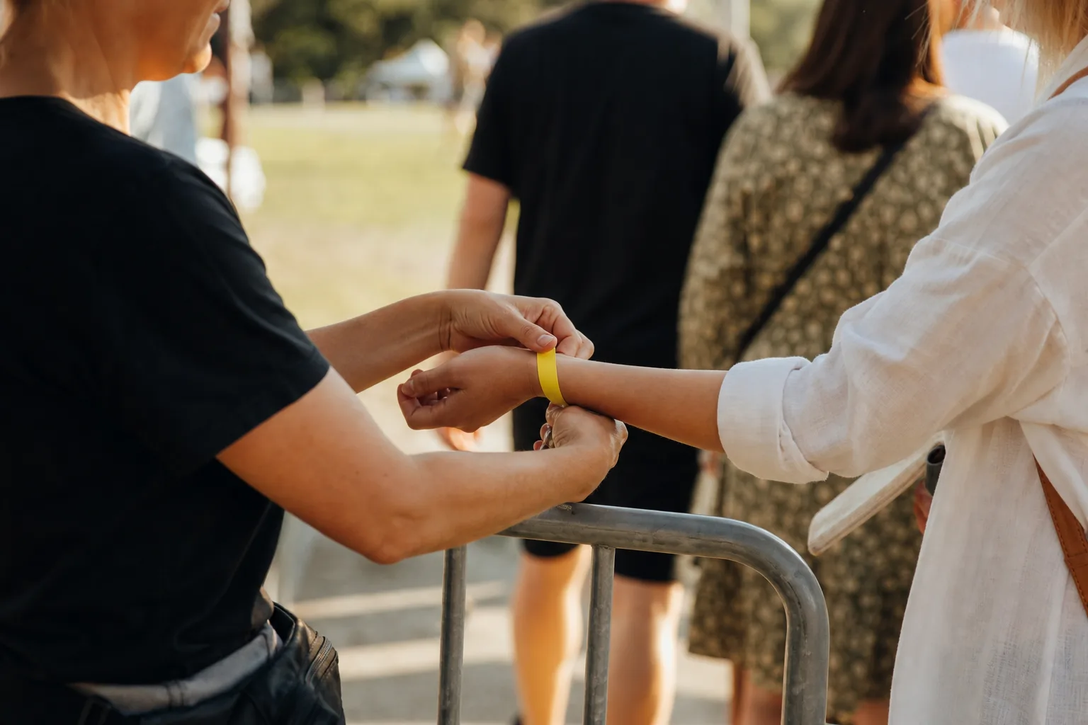Funktionär kontrollerar ett armband vid en liten eventgrind.