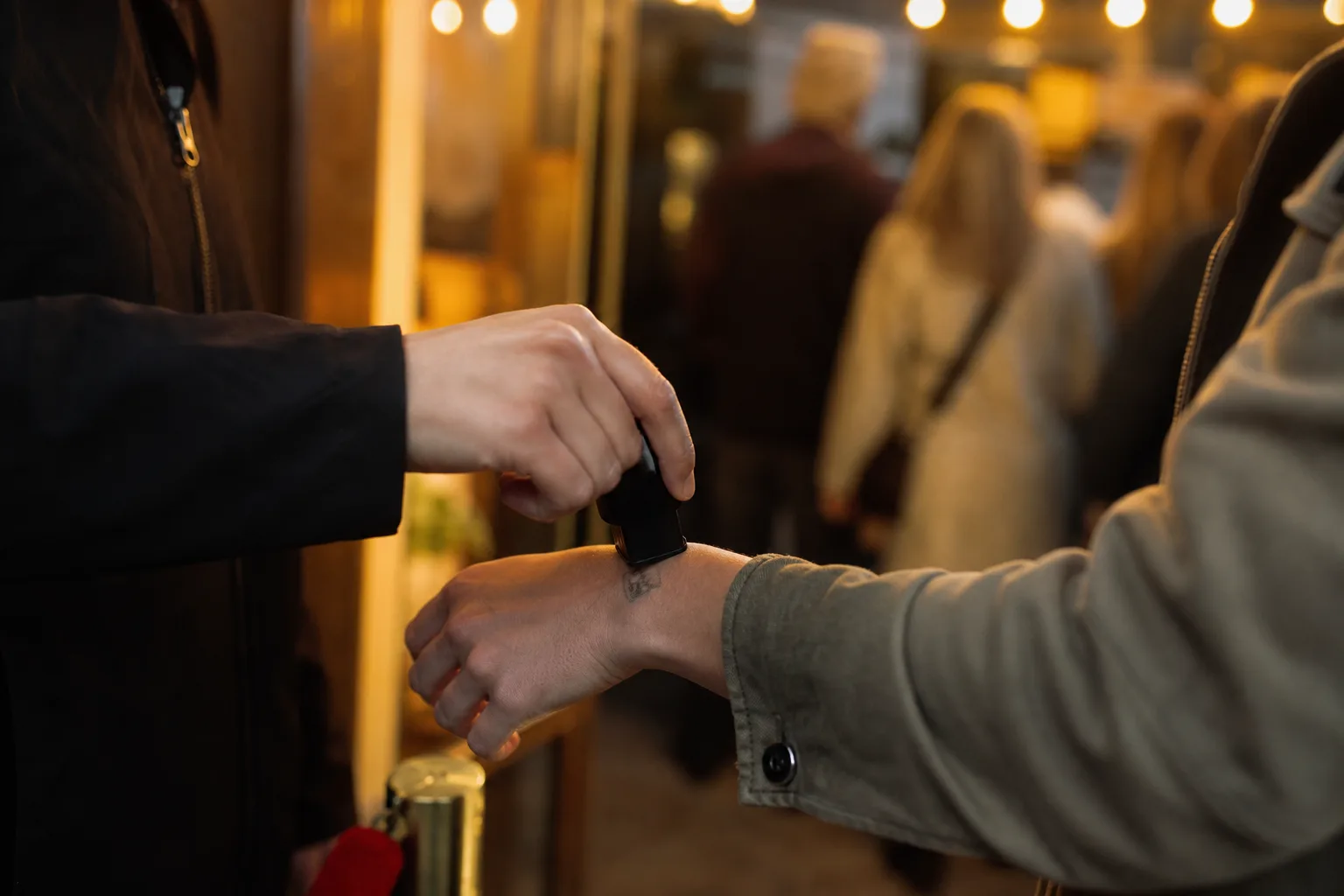 Funktionär stämplar en hand vid en kvällsentré.
