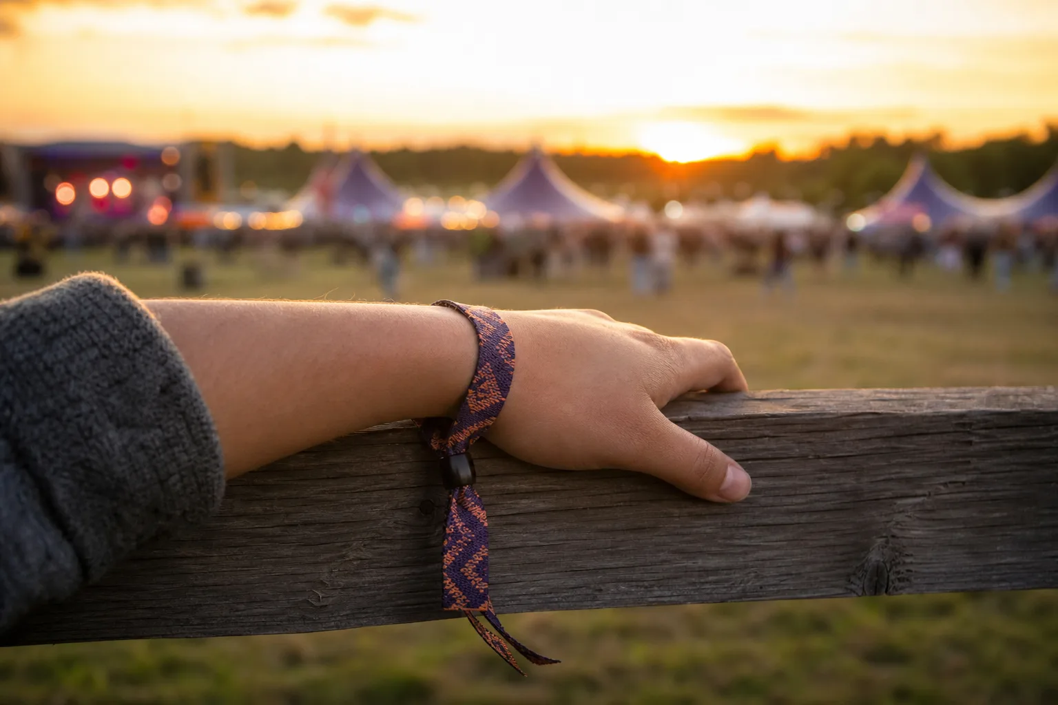Vävt tygarmband på handled vid festivalområde i kvällsljus.